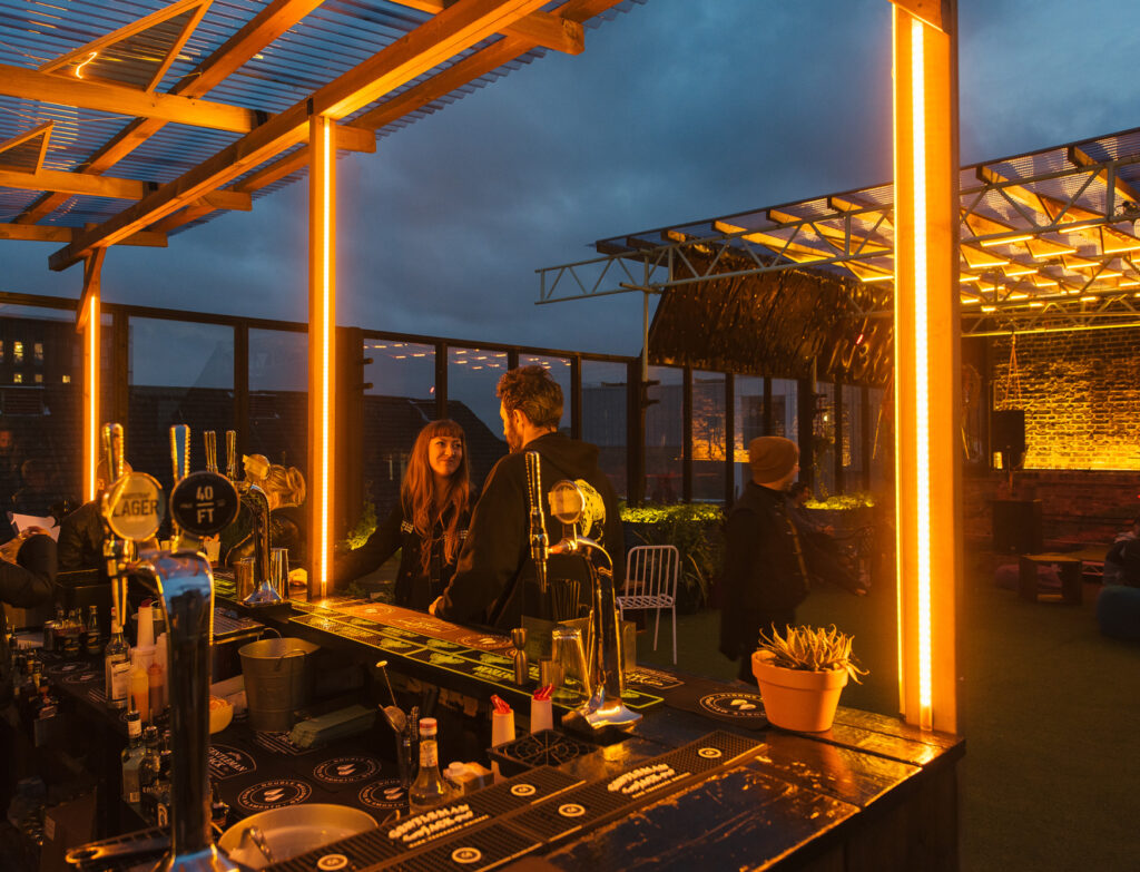 Bespoke lighting design bu Michael Grubb Studio transforms Dalston Roofpark into a dynamic event space, using warm-toned filters, integrated LEDs, and sustainable solutions to enhance the atmosphere after dark.